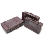 A set of three crimson fibre-covered graduated suitcases.