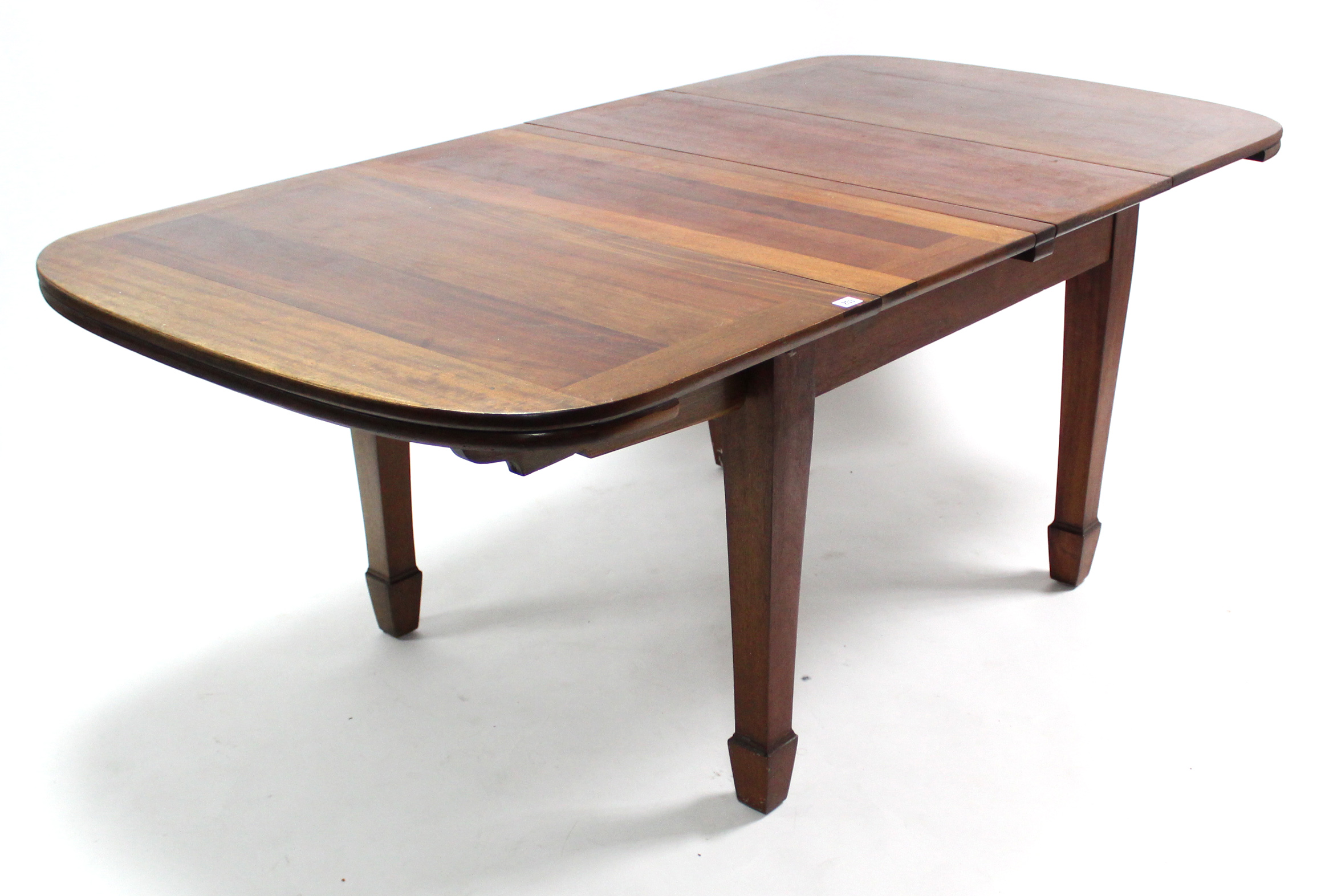 An Edwardian mahogany extending dining table with rounded corners to the rectangular top, pull-out