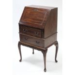 A reproduction mahogany small bureau, with fitted interior enclosed by fall-front above two long