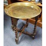 A small brass tray-top occasional table on oak folding stand with barley-twist legs, 16” diam.; a