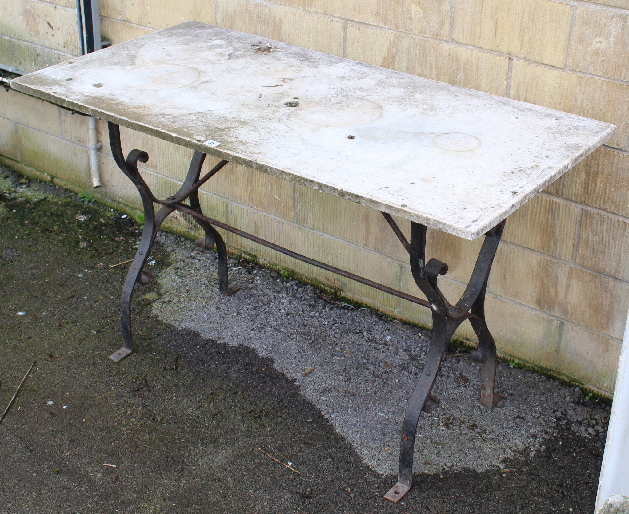 A wrought-iron garden table, with shaped end supports joined by plain centre stretchers & with white