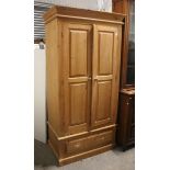 A pine wardrobe enclosed by pair of panel doors above a deep long drawer, & on plinth base, 39½”