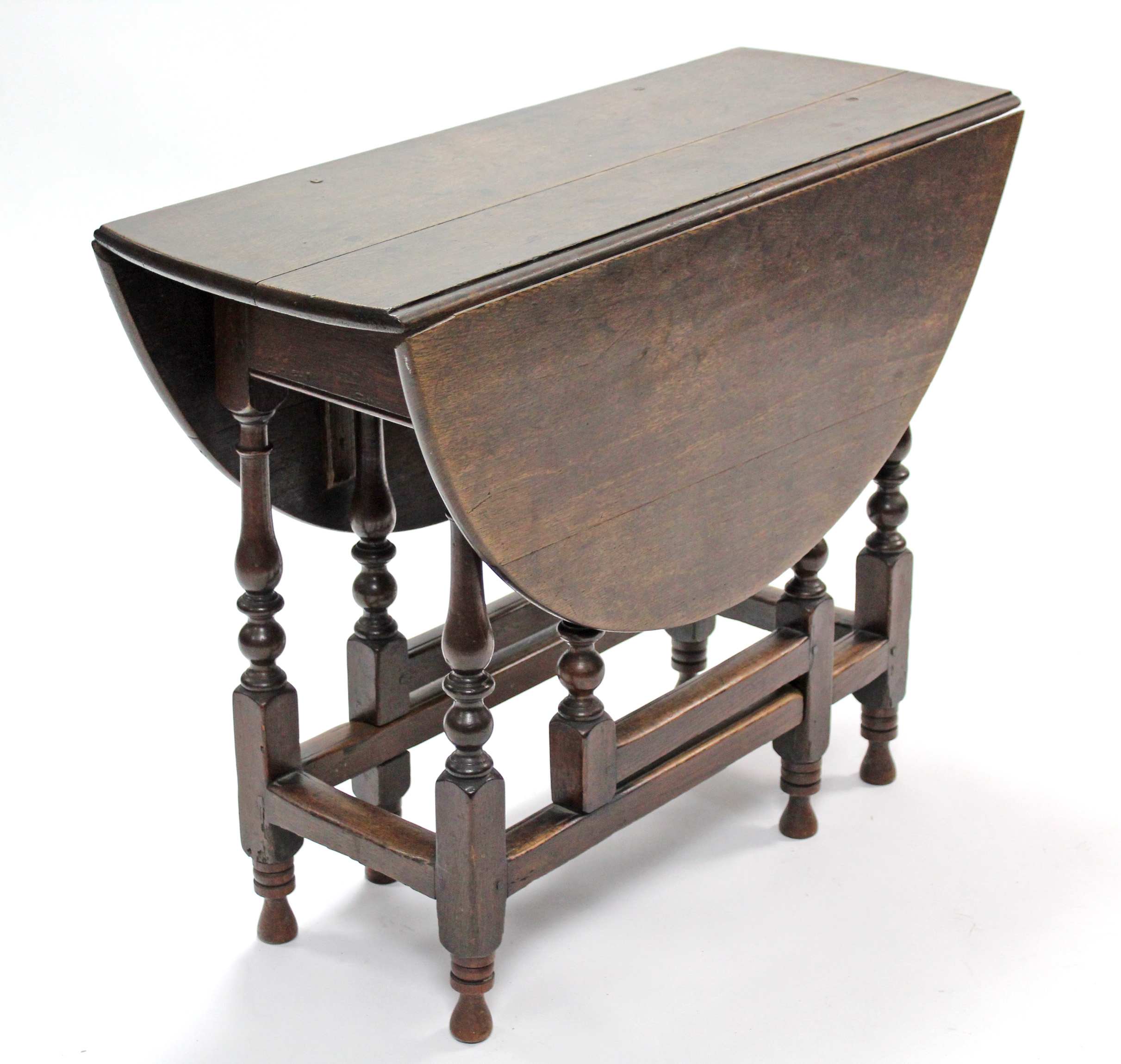 An 18th century oak gate-leg table with oval top, on slender turned supports with plain