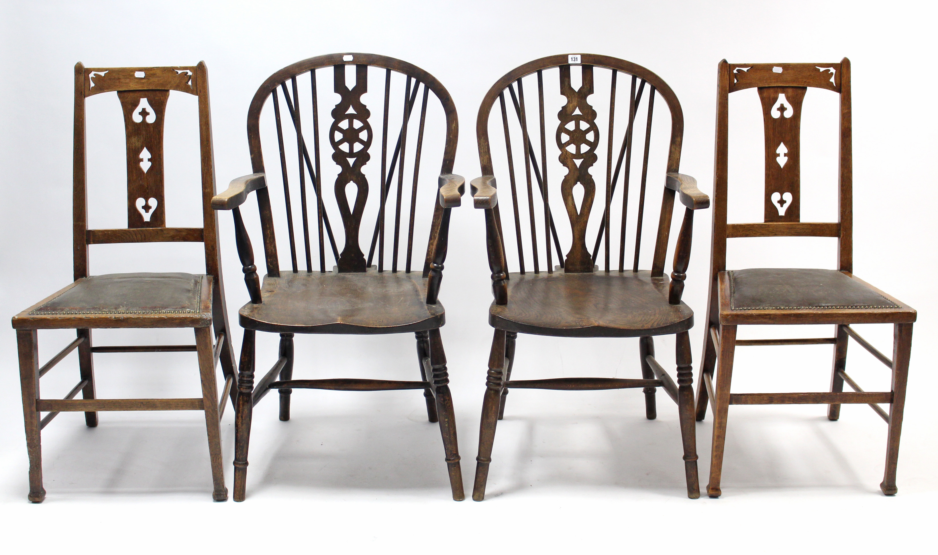 A pair of wheel back carver chairs with hard seats & on turned legs with spindle stretchers; & a