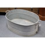 A galvanised-metal oval two-handled baby’s bath, 28” x 20½”.