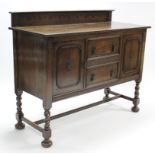 A 1930’s oak sideboard, fitted two long drawers to centre flanked by cupboard to either end enclosed