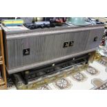 A mid-20th century brown & cream laminate sideboard enclosed by two pairs of pane doors, & on