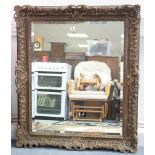 A large gilt frame rectangular wall mirror with raised & pierced scroll border & inset bevelled