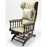 A late Victorian beech-frame wing-back rocking chair upholstered cream & green striped floral