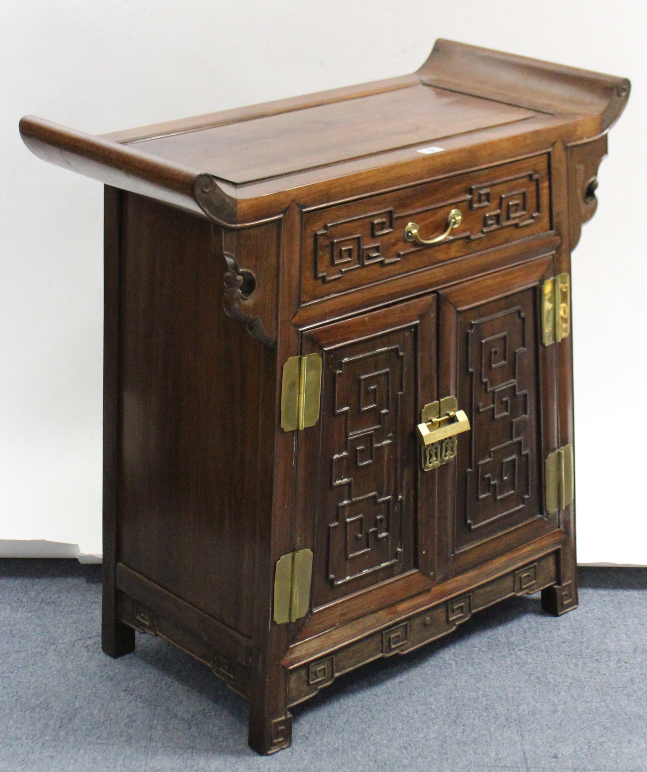 A Chinese carved teak side cabinet, fitted frieze drawer above cupboard enclosed by pair of panel