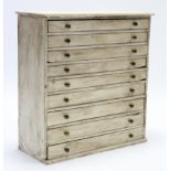 A white painted pine collector’s chest, fitted nine drawers with brass knob handles, 25¾” wide x 27”