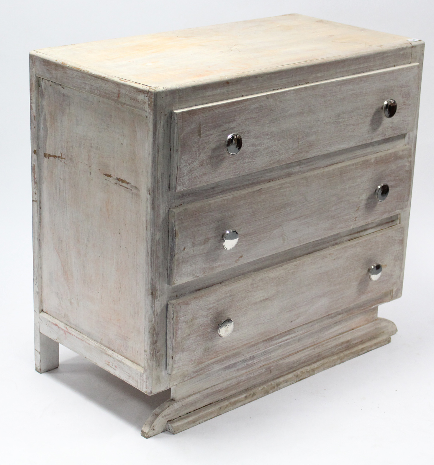 A continental-style white painted wooden dwarf chest fitted three long drawers, & on shaped plinth