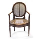 A 19th century carved French fauteuil with cane back & seat, open scroll arms, & on fluted