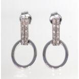 A pair of diamond earrings, each with an articulated oval loop suspended from a baton millegrain-set