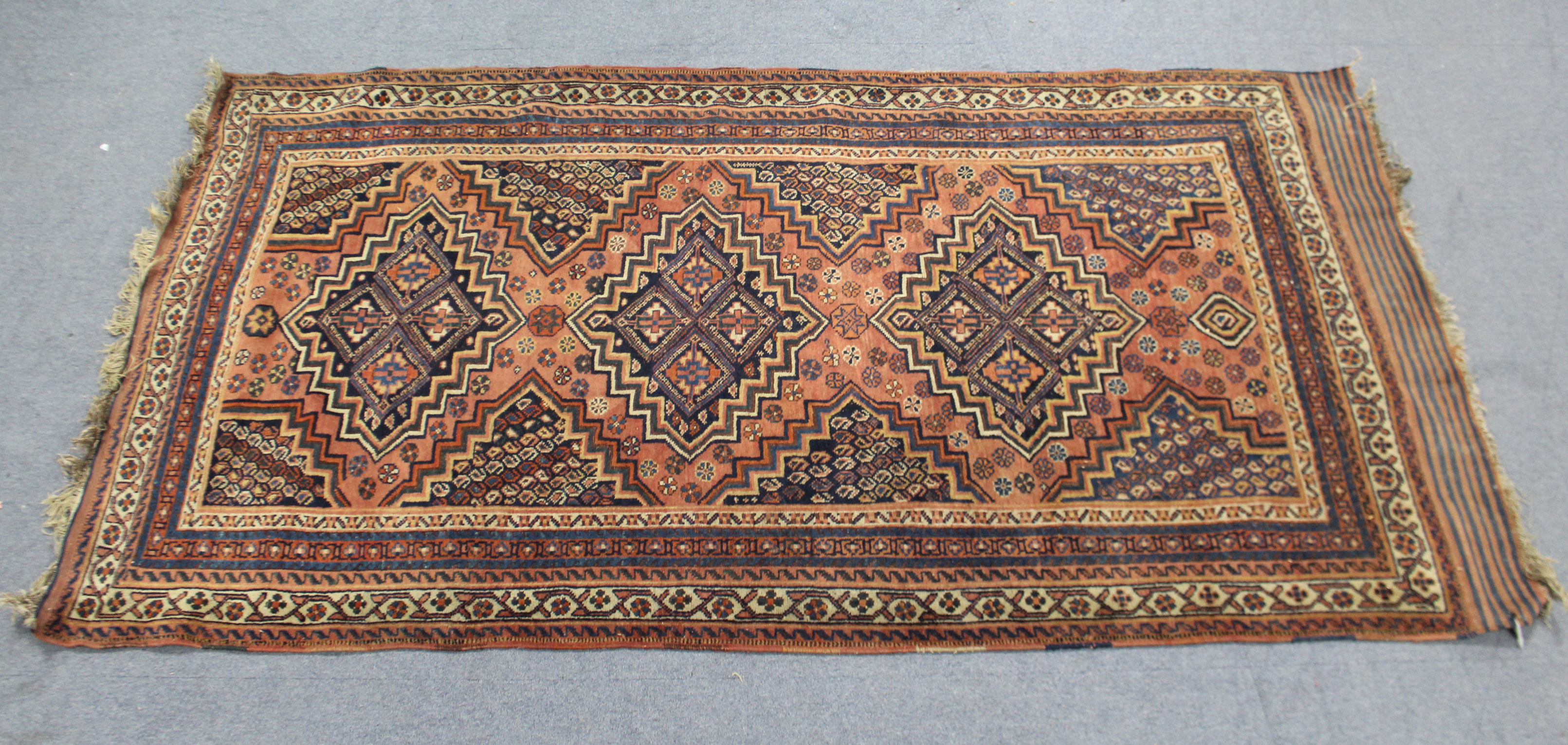 A Persia rug of crimson ground, with repeating geometric lozenge & star pattern within multiple