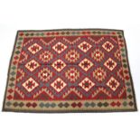 A Kelim rug of deep red ground with central panel of multicoloured lozenges within a geometric