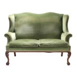 A Chippendale-style two seater wing-back sofa, the shaped back, scroll arms, & loose cushion seats