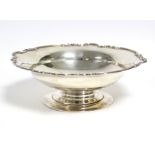 A George V silver shallow circular dish with scroll border, on pedestal foot, 9” diam., London 1938,