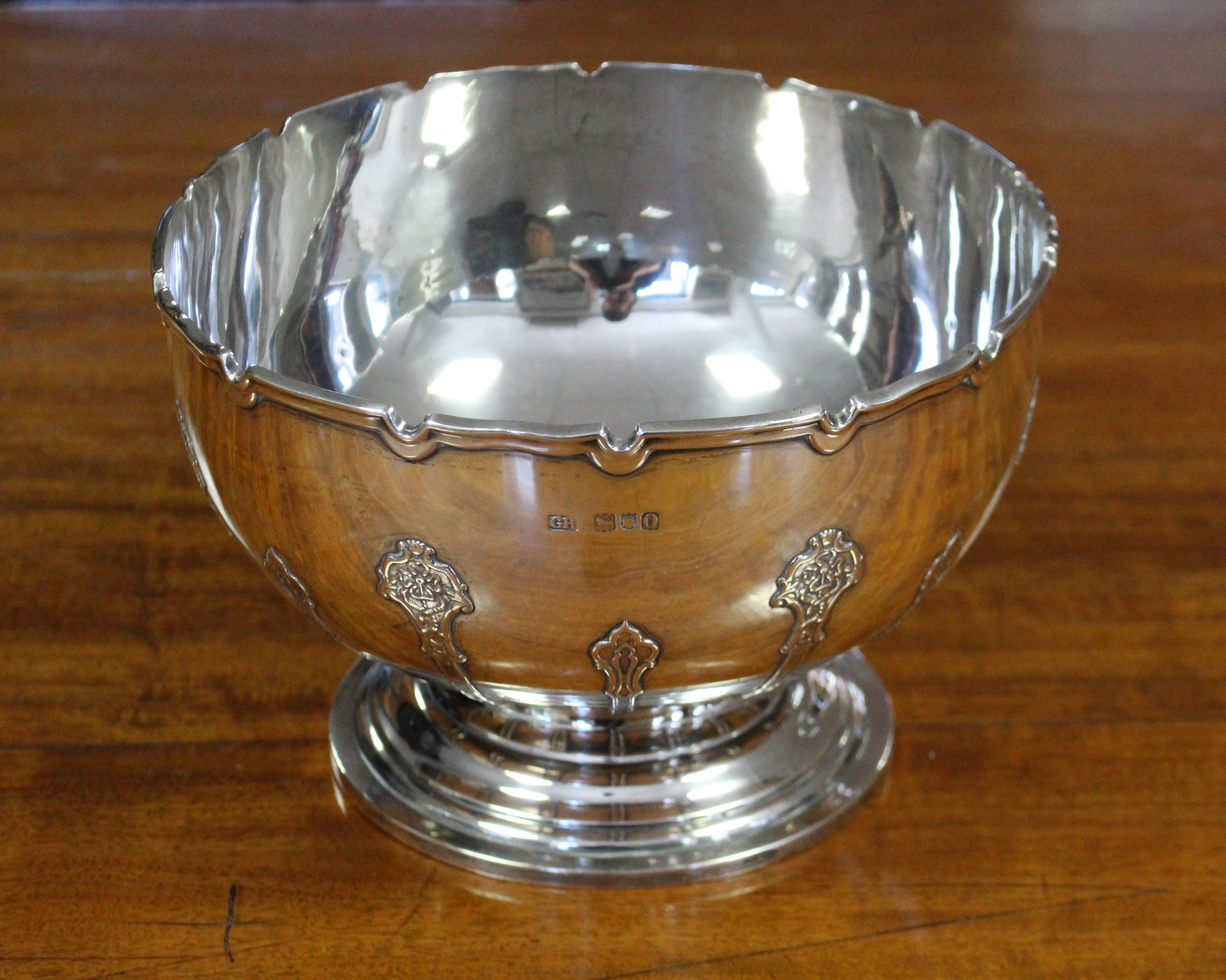 An Edwardian silver punch bowl with indented rim, the body decorated with raised strapwork, on round