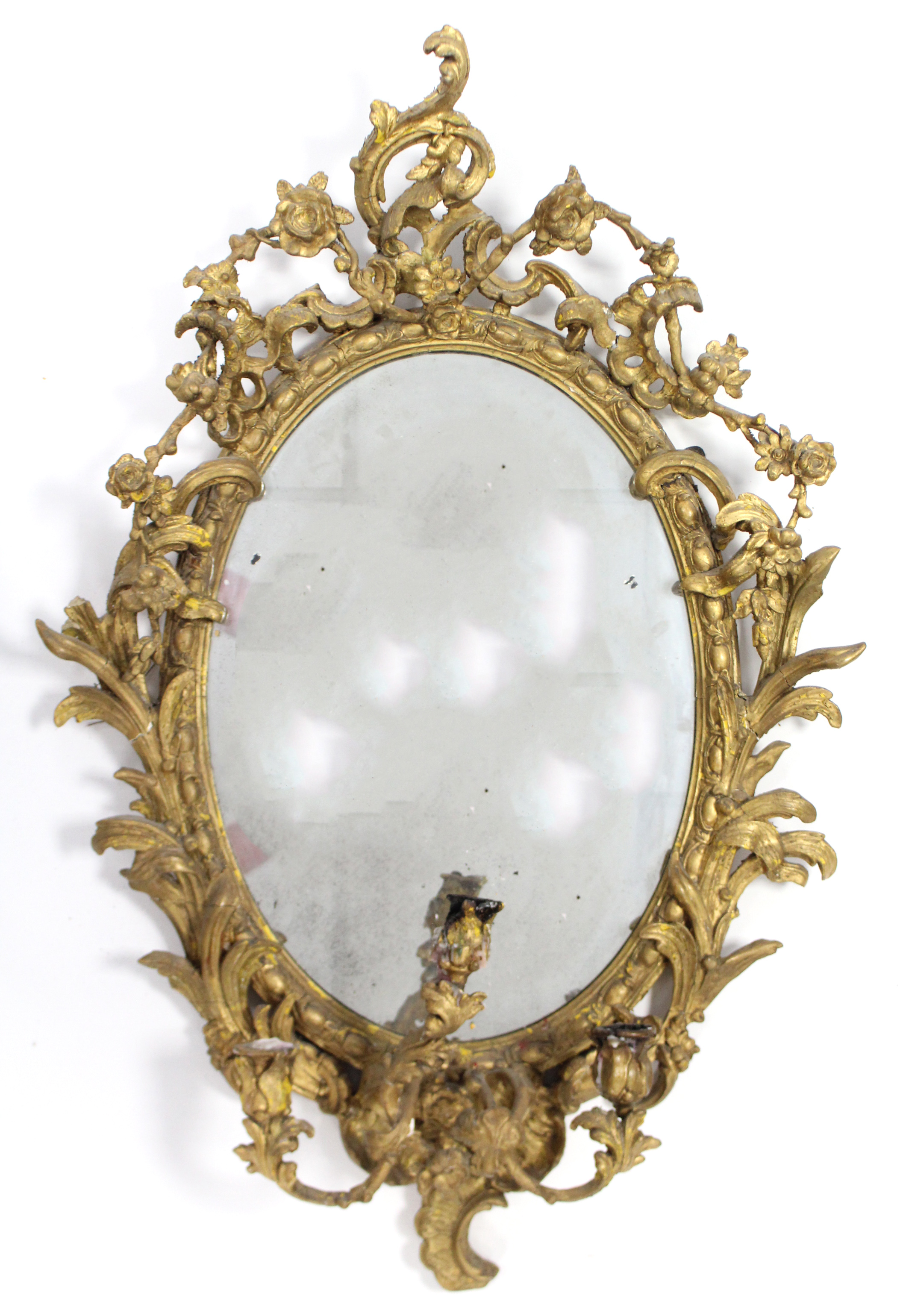 An early 19th century girandole, the oval mirror plate in gilt gesso rococo frame with floral