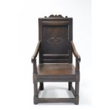 A 17th century joined oak Wainscot chair, with carved lozenge to the panel back, foliate scroll