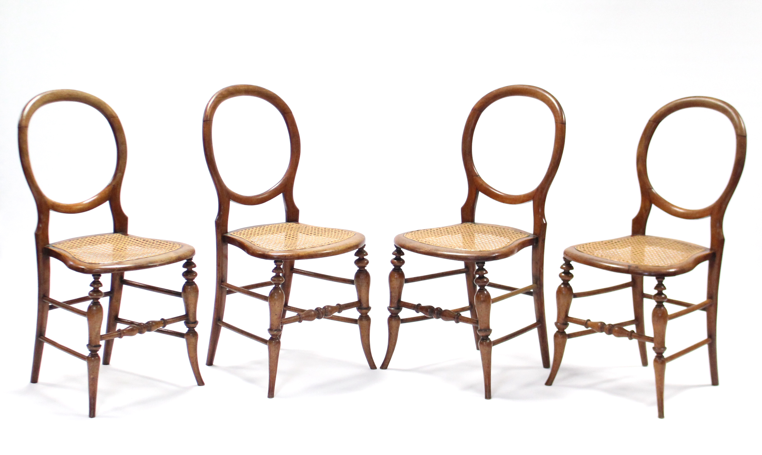 A set of four stained beech balloon-back side chairs with open backs & woven cane seats, on