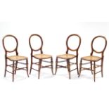 A set of four stained beech balloon-back side chairs with open backs & woven cane seats, on