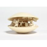 A Japanese ivory netsuke carved in the form of an open clam shell, the interior with scene of