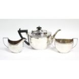 A George V silver three-piece tea service of plain oval form with narrow foliate rims; London