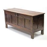 An 18th century oak coffer with four-panel front & two-board hinged lid; 62” wide.