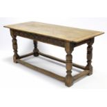 A 17th century style oak refectory table with two-board rectangular top, carved frieze, & on