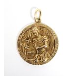 An un-marked yellow metal circular pendant cast with a figure of Saint Genesius, patron saint of
