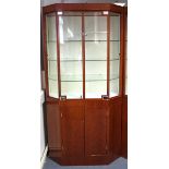 A modern mahogany-finish upright illuminated shop display cabinet with canted sides, fitted three