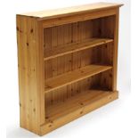 A pine standing open bookcase with two adjustable shelves, & on plinth base, 48½” wide x 42” high.