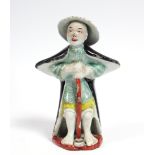 A Chinese porcelain standing male figure wearing wide brimmed hat & black cape; 6” high (slight