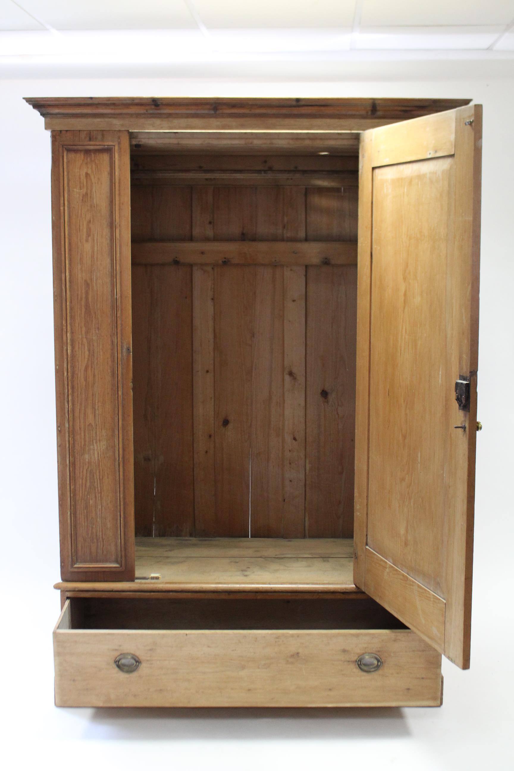 A pine wardrobe with moulded cornice, enclosed by centre panel door, & fitted deep long drawer to - Image 2 of 3