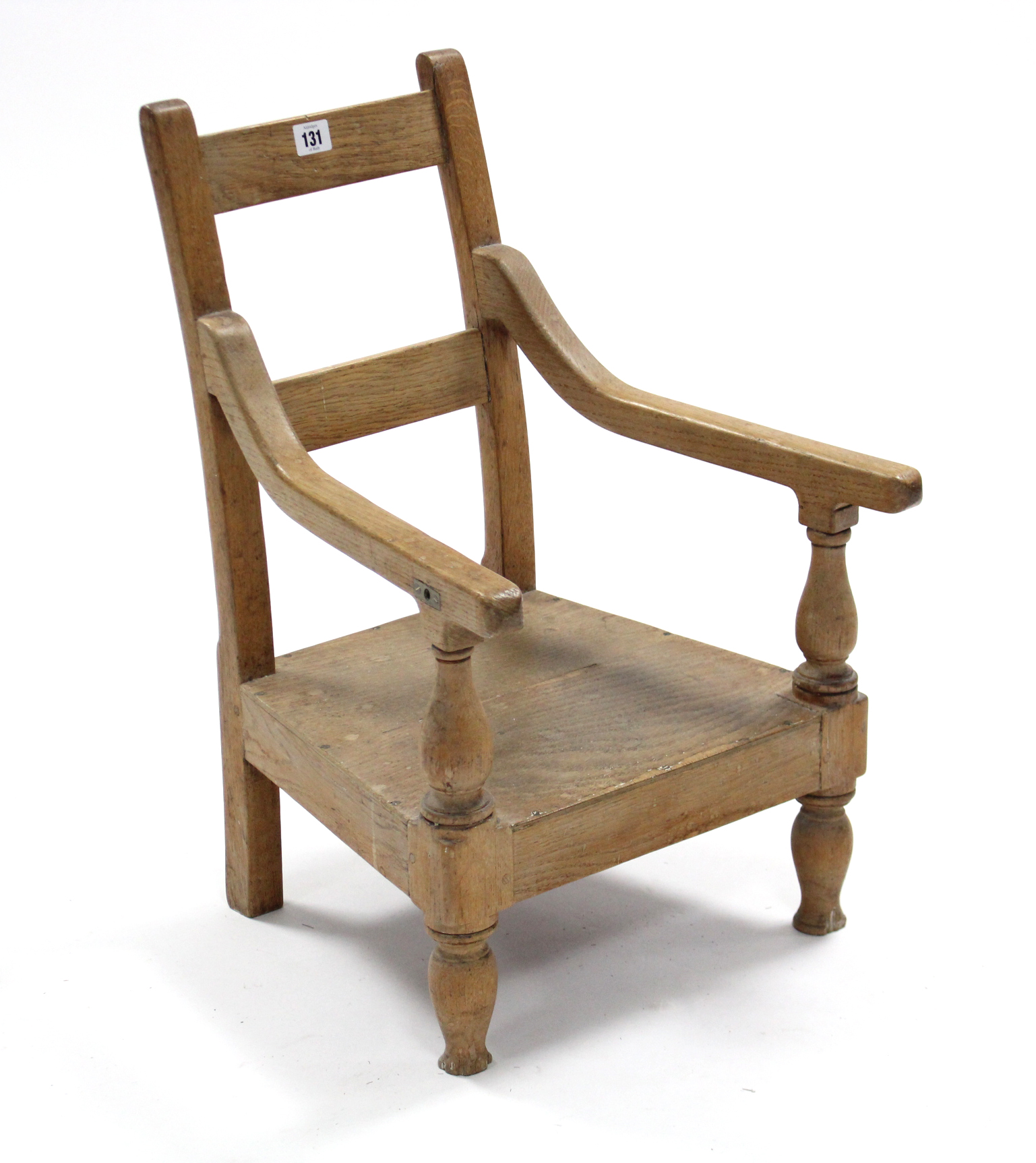 A light oak child’s rail-back elbow chair with hard seat & on turned legs.