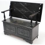 A reproduction ebonised carved oak monk’s bench with fold-over box-seat, & on bracket feet, 48” wide