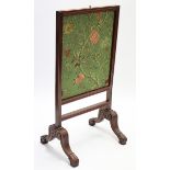 A 19th century mahogany fire screen with embroidered rise-&-fall panel, & on carved cabriole legs,