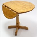 A maple-finish circular drop-leaf kitchen table on turned centre column & four splay legs, 36”