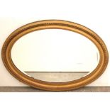 A gilt frame oval wall mirror with egg-&-dart border, & inset bevelled plate, 25” x 34¾”.