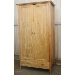 A maple-finish wardrobe, enclosed by pair of panel doors above a long drawer, 39¼” wide x 74¾”