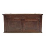 An early 20th century oak dwarf cupboard enclosed by hinged lift-lid above a pair of panel doors,