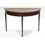 A mahogany demi-lune side table on three square tapered legs, 43¾” wide.