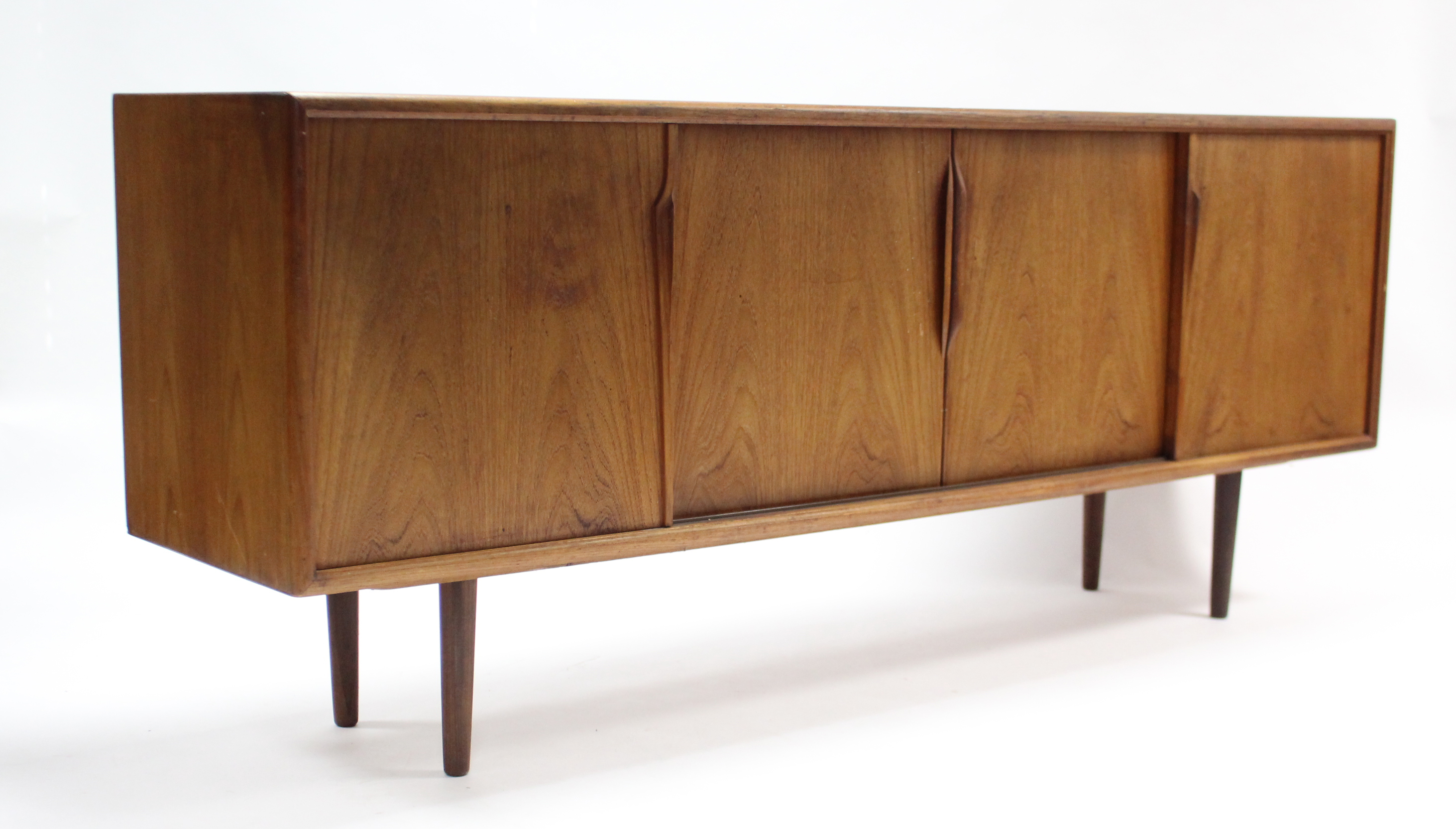 A 1960’s teak sideboard with fitted interior enclosed by two pairs of sliding panel doors, & on