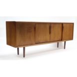 A 1960’s teak sideboard with fitted interior enclosed by two pairs of sliding panel doors, & on