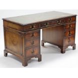 A reproduction mahogany pedestal desk, inset gilt-tooled green leather cloth, fitted with an