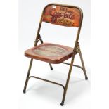 A modern painted metal folding chair inscribed: “Drink Coca-Cola In Bottles”.