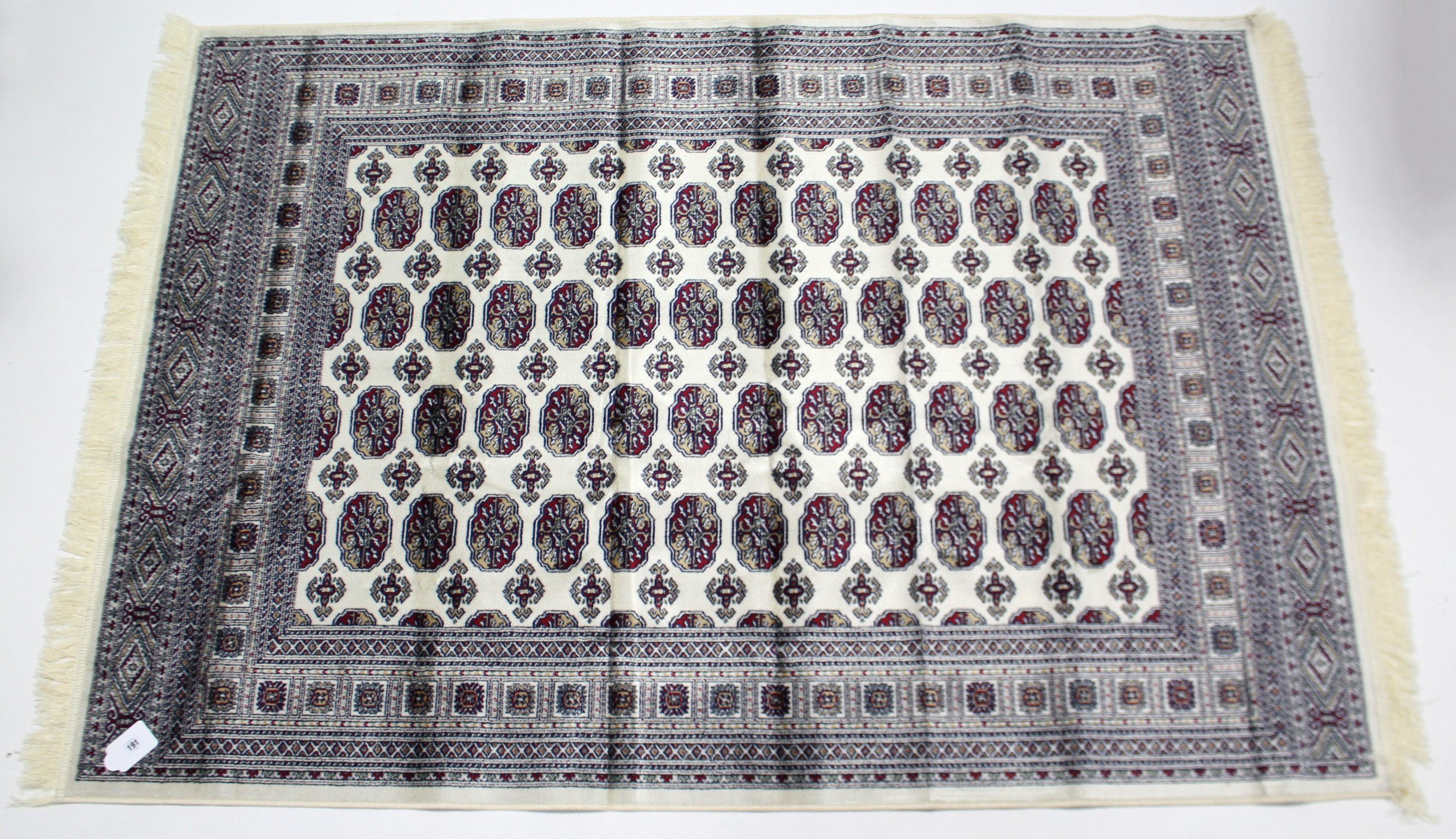 A Bokhara rug of beige & crimson ground & with four rows of twelve guhls to centre within a multiple