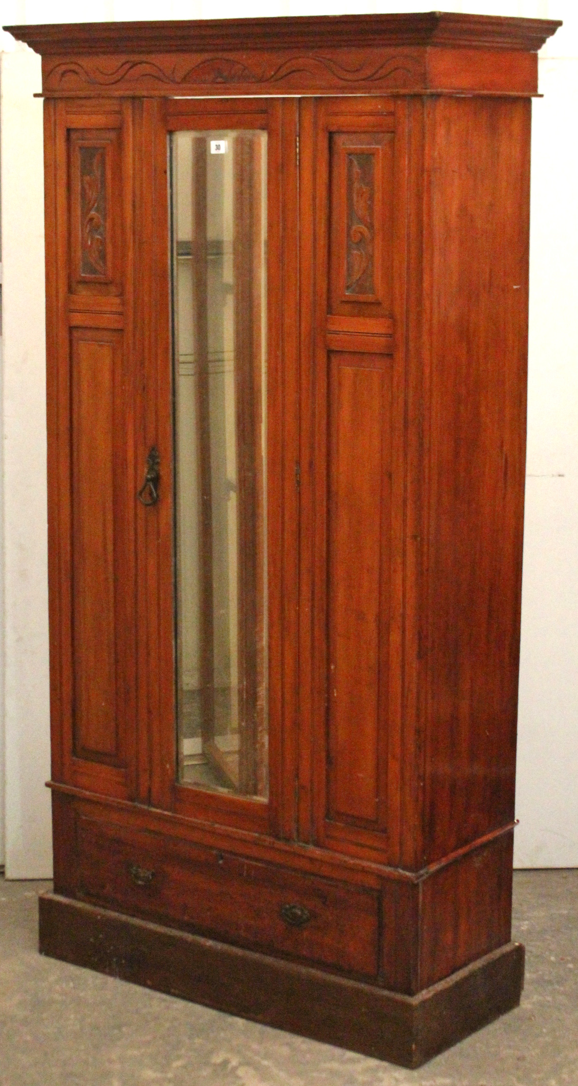 A late Victorian carved mahogany small wardrobe enclosed by rectangular bevelled mirror door to